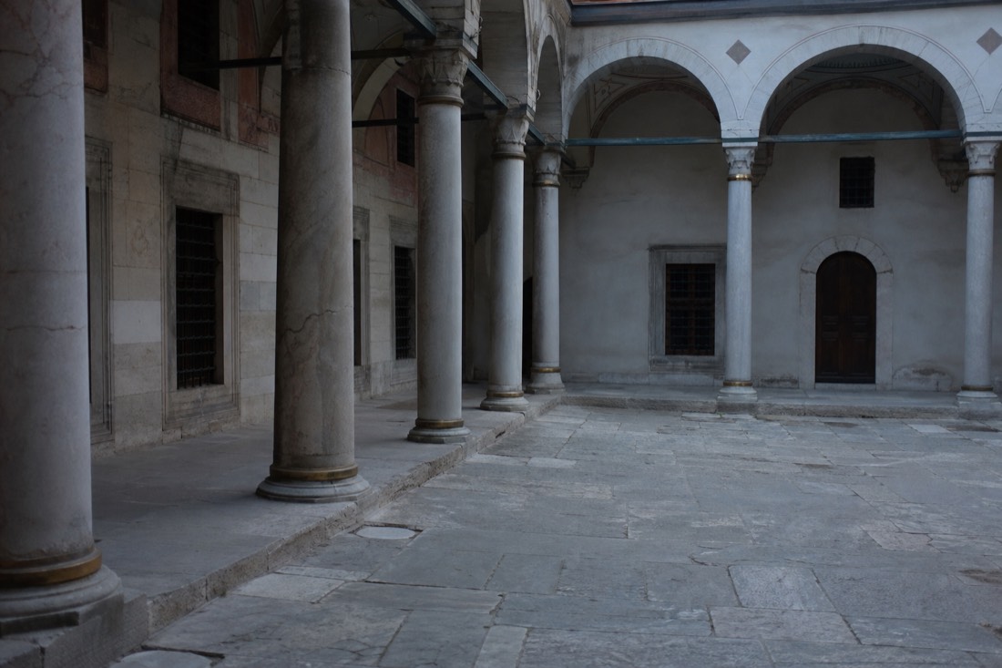 Narrow stone courtyard with weathered columns inside the Topkapi Palace Harem on a quiet morning
