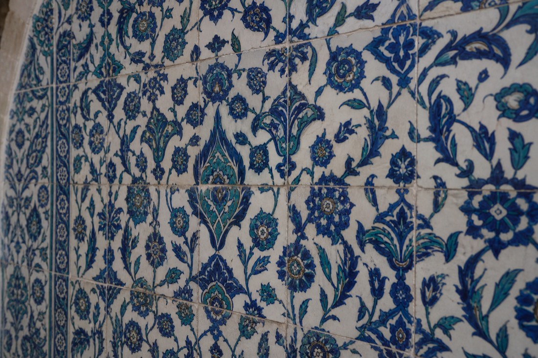 A blue-and-white Iznik tile panel detail on a Topkapi Palace wall in soft daylight