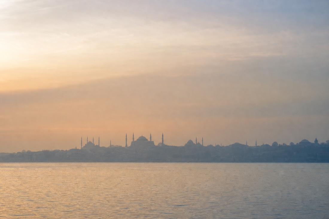 The silhouette of Istanbul's old-city skyline with minarets across the water at dawn haze