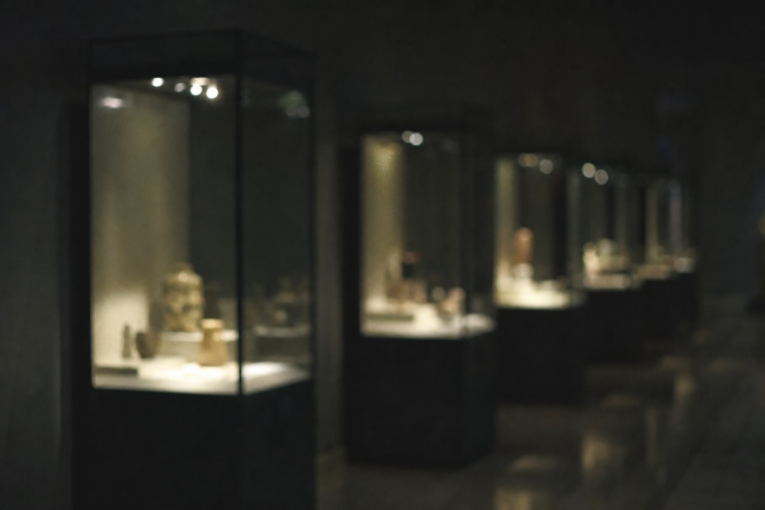 Dim museum gallery inside the Topkapi Palace treasury with glass display cases glowing softly in low light