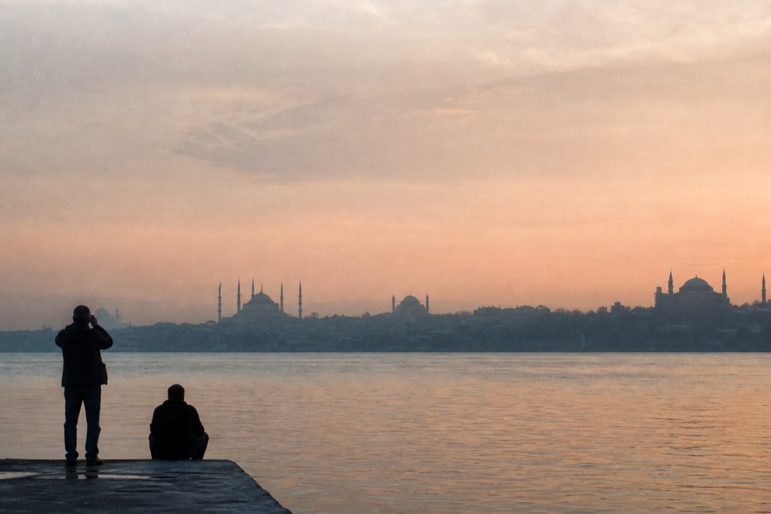 Silhouette of Istanbul's old-city skyline with minarets across the water in dawn haze
