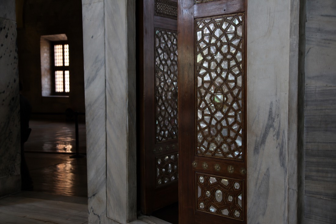 Marble Topkapi Palace doorway with mother-of-pearl inlaid doors seen at an angle in dim light