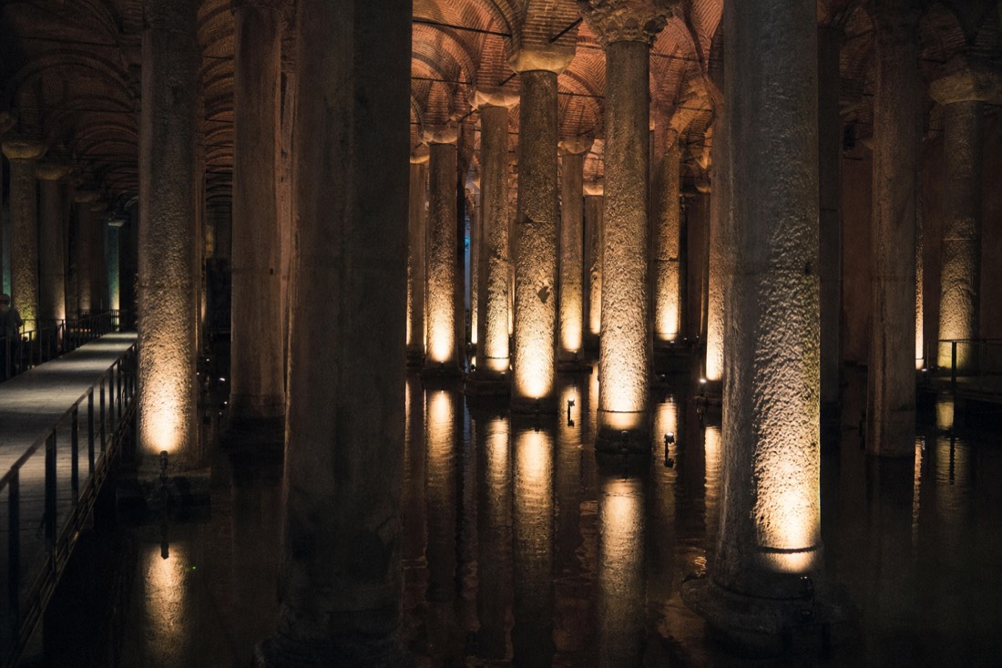 The columned underground hall of the Basilica Cistern in Istanbul lit in warm light above dark water
