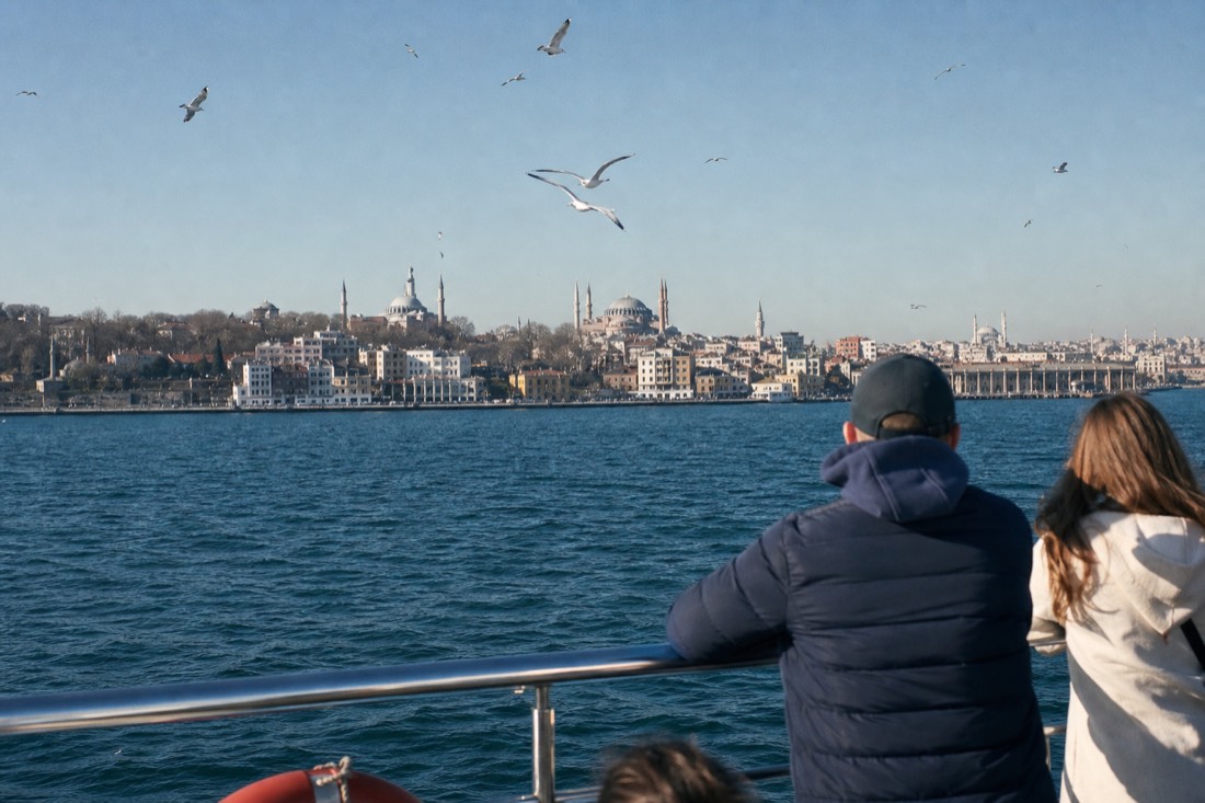 A sightseeing boat on the Bosphorus in Istanbul with the old-city skyline and minarets behind it